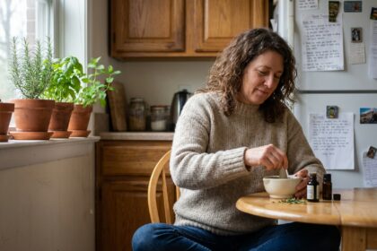 Femme assise en cuisine mélangeant des huiles essentielles