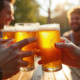 Groupe d'amis trinquant avec bières sans gluten sur terrasse ensoleillee